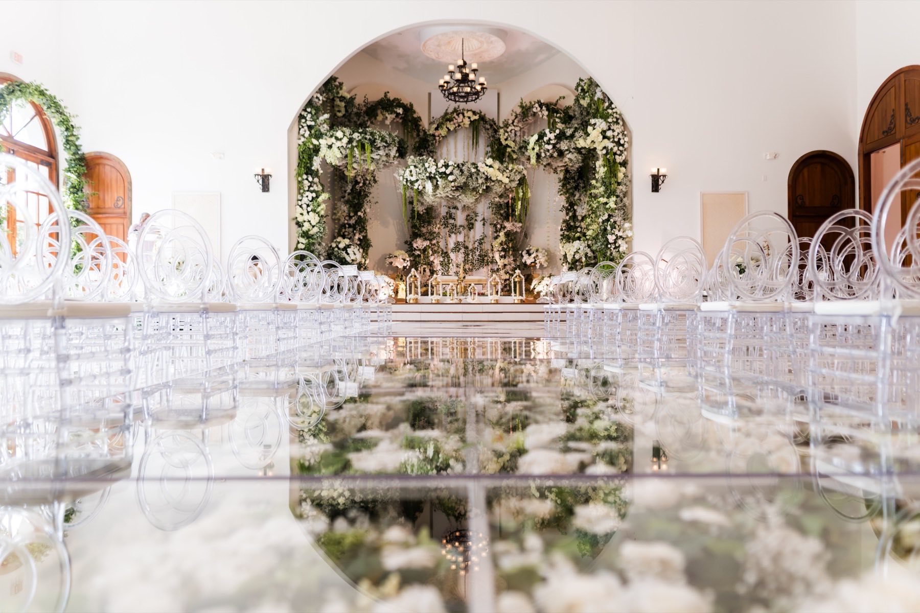Outdoor ceremony venue with vibrant pink and orange floral arch and white chiavari chairs