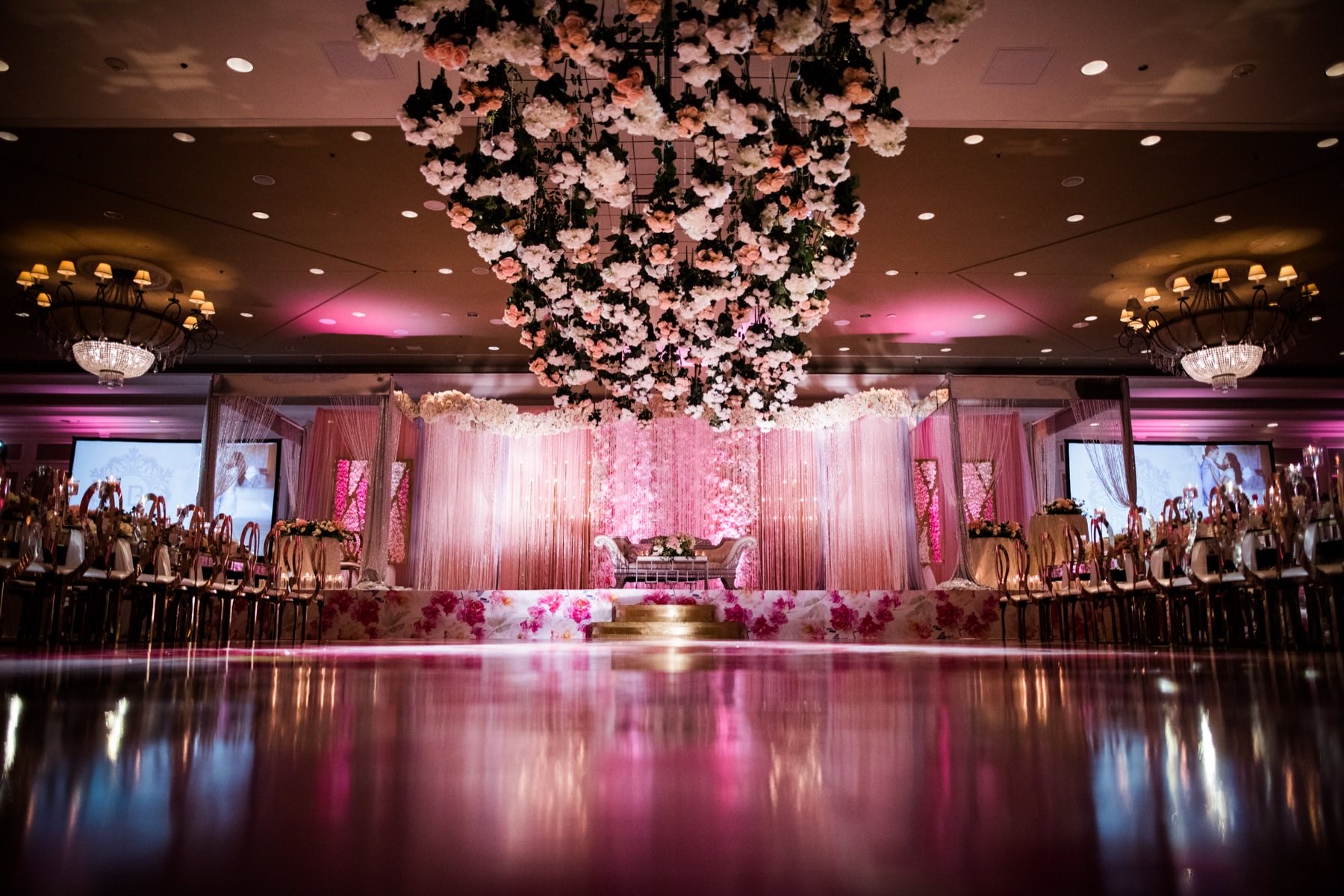 Pink ballroom reception with cascading hanging floral installation above dance floor