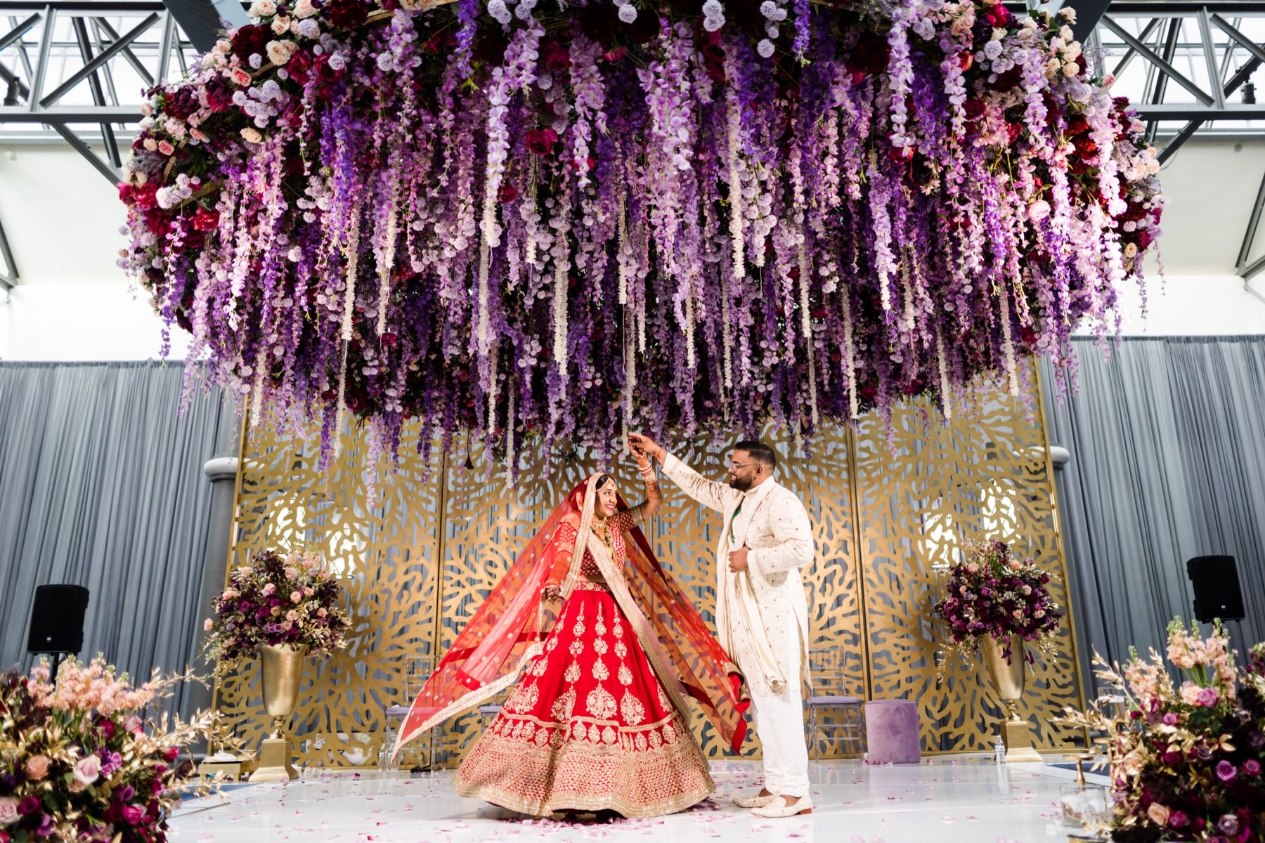Couple at ceremony beneath hanging florals