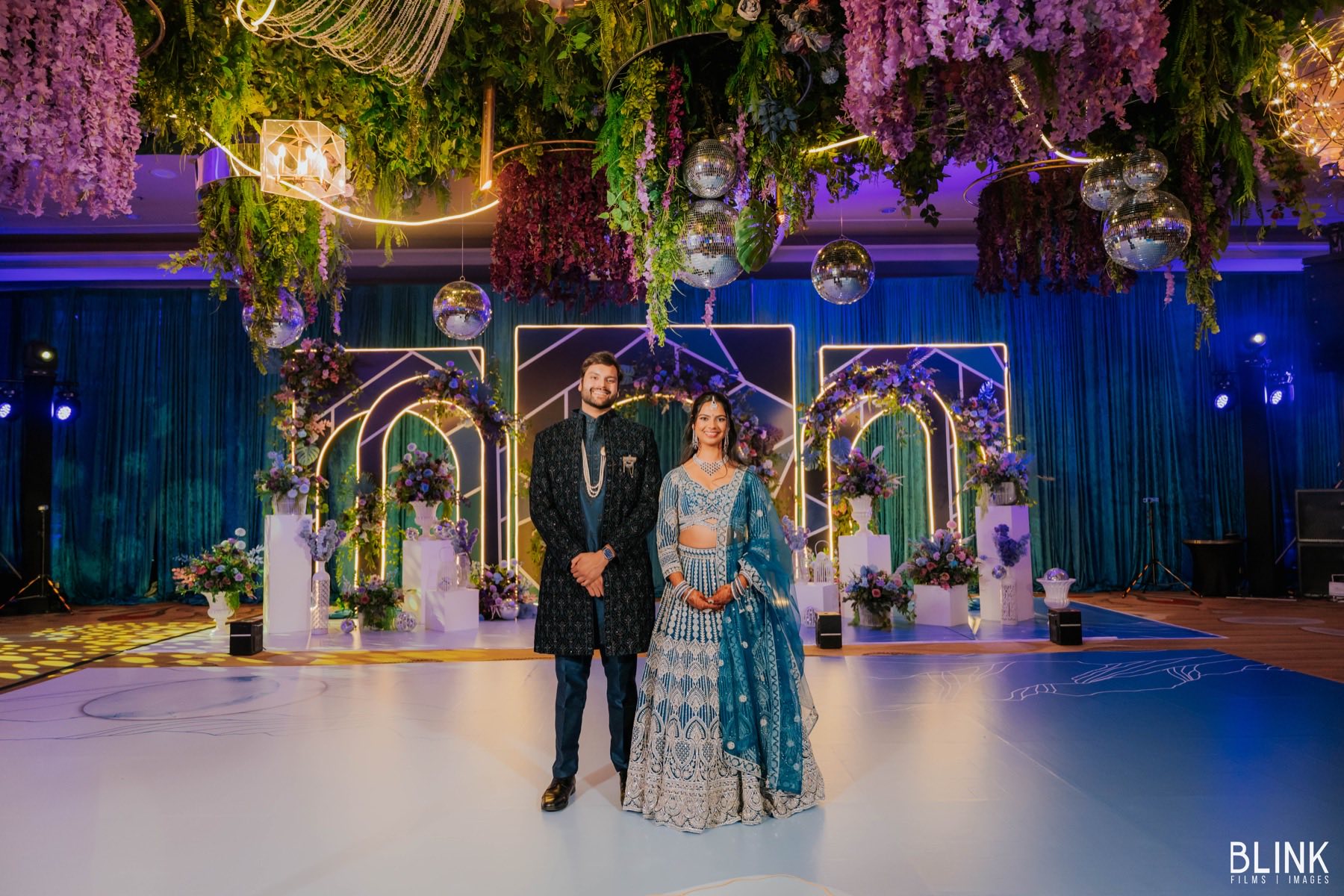 Energetic sangeet performance with vibrant stage decorations and uplighting