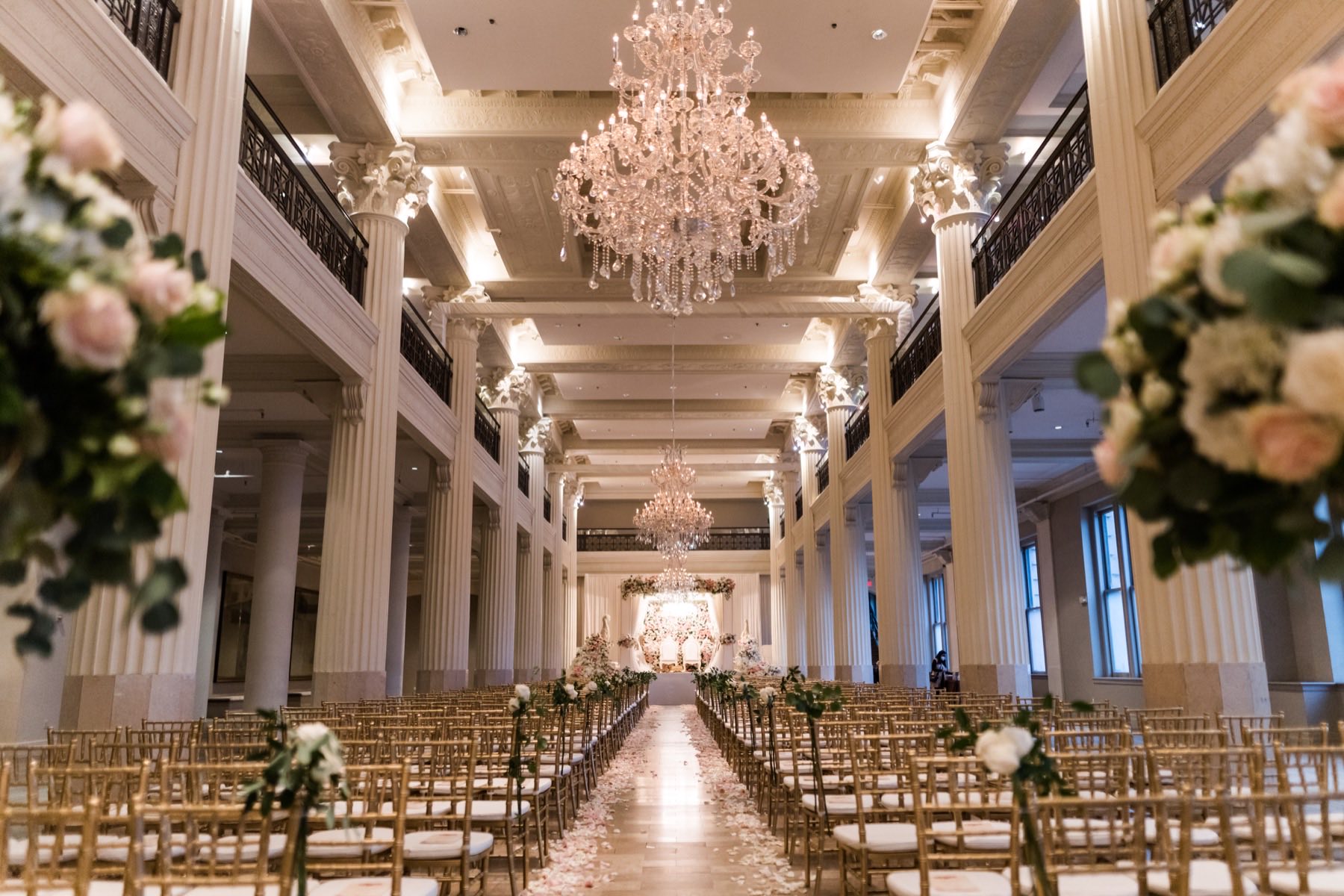 Grand ceremony hall with crystal chandeliers and rose petal aisle leading to the altar