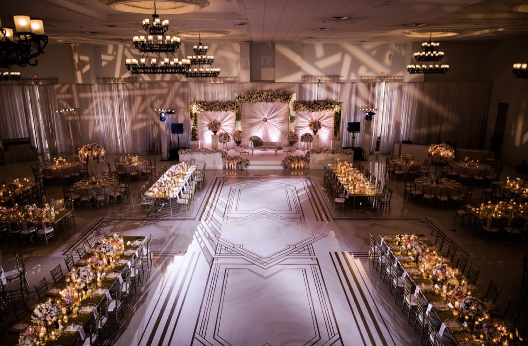 Aerial view of grand reception ballroom with geometric gold-lined dance floor and chandeliers
